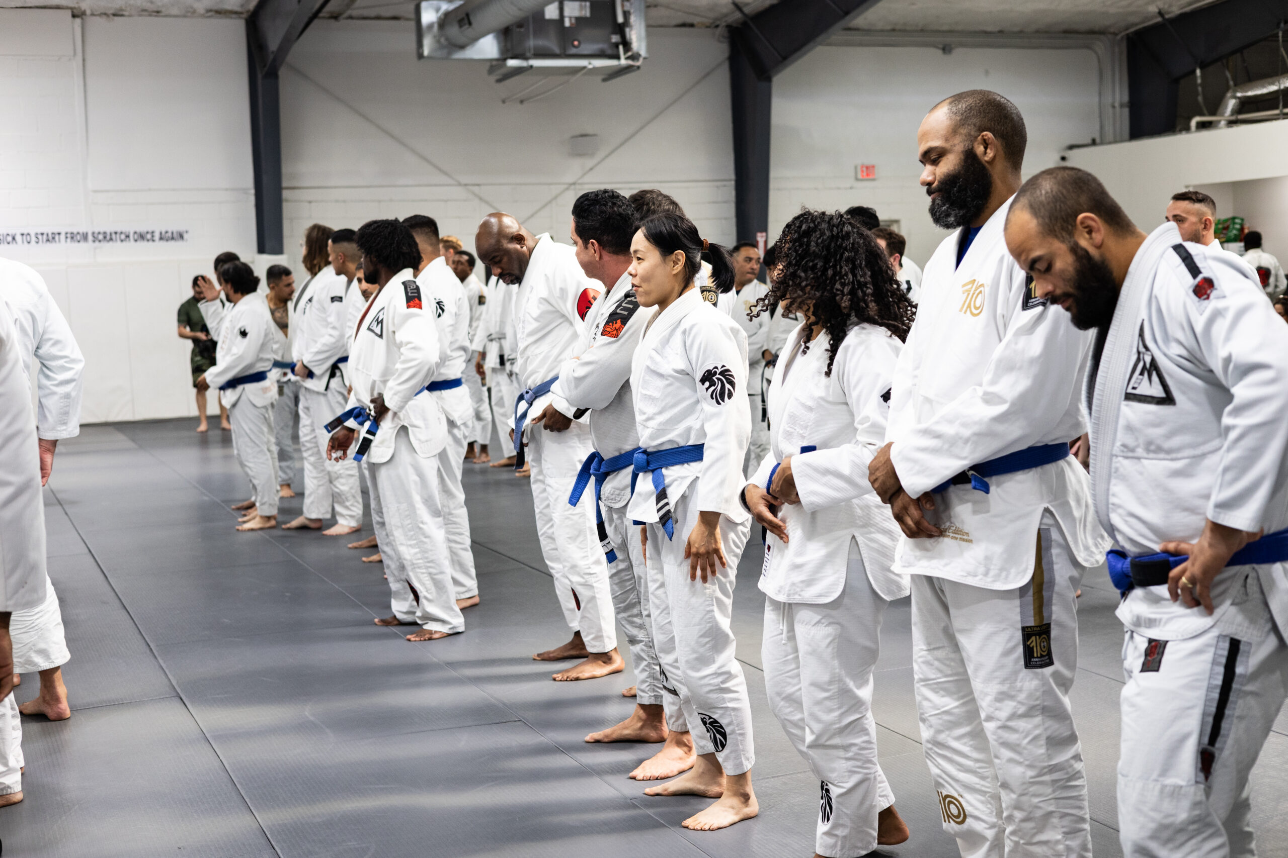 Adult martial arts practitioner refining positional control during sparring session on academy mats.
