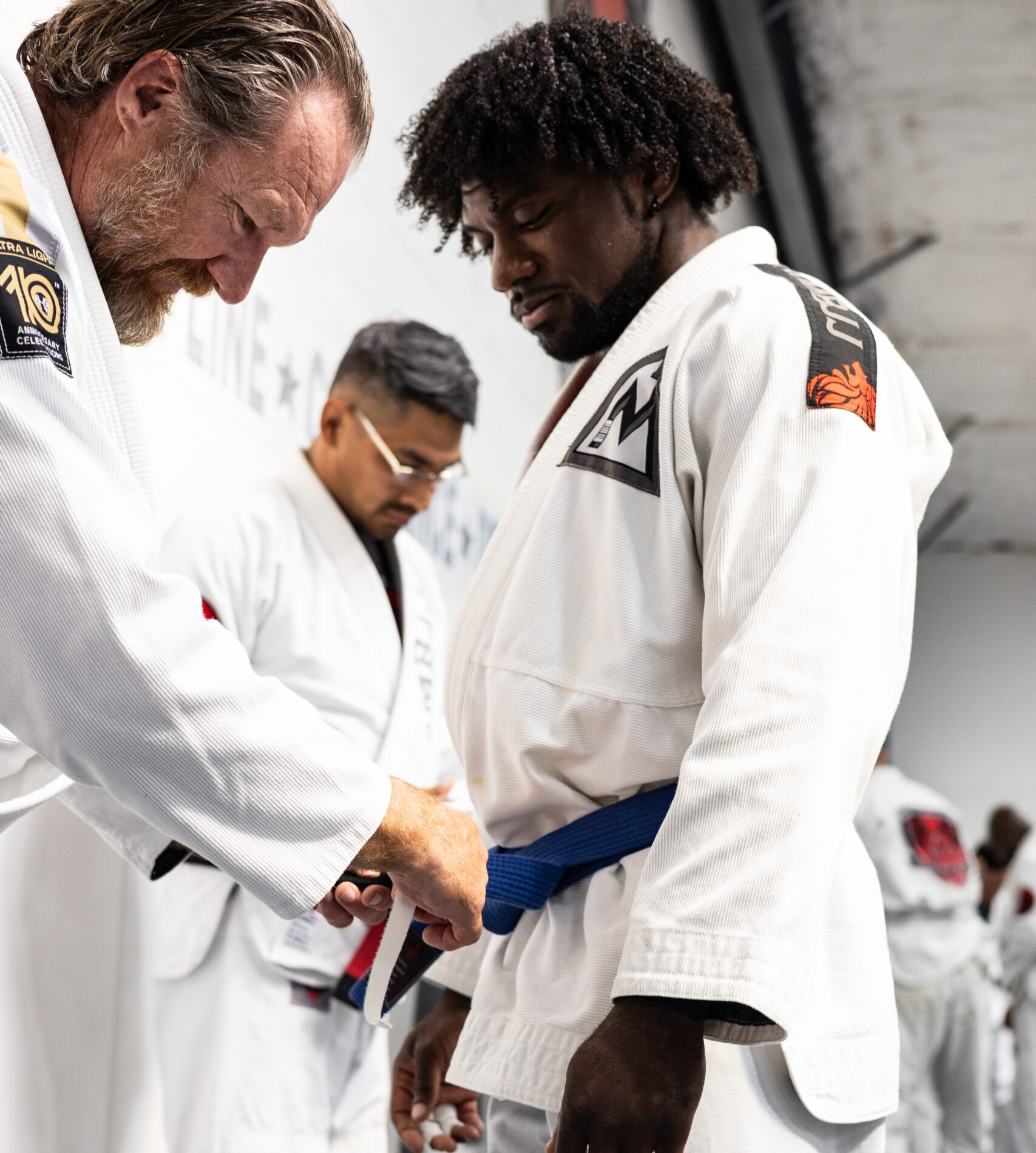 Martial arts instructor guiding student through precise joint lock submission control during grappling drill.